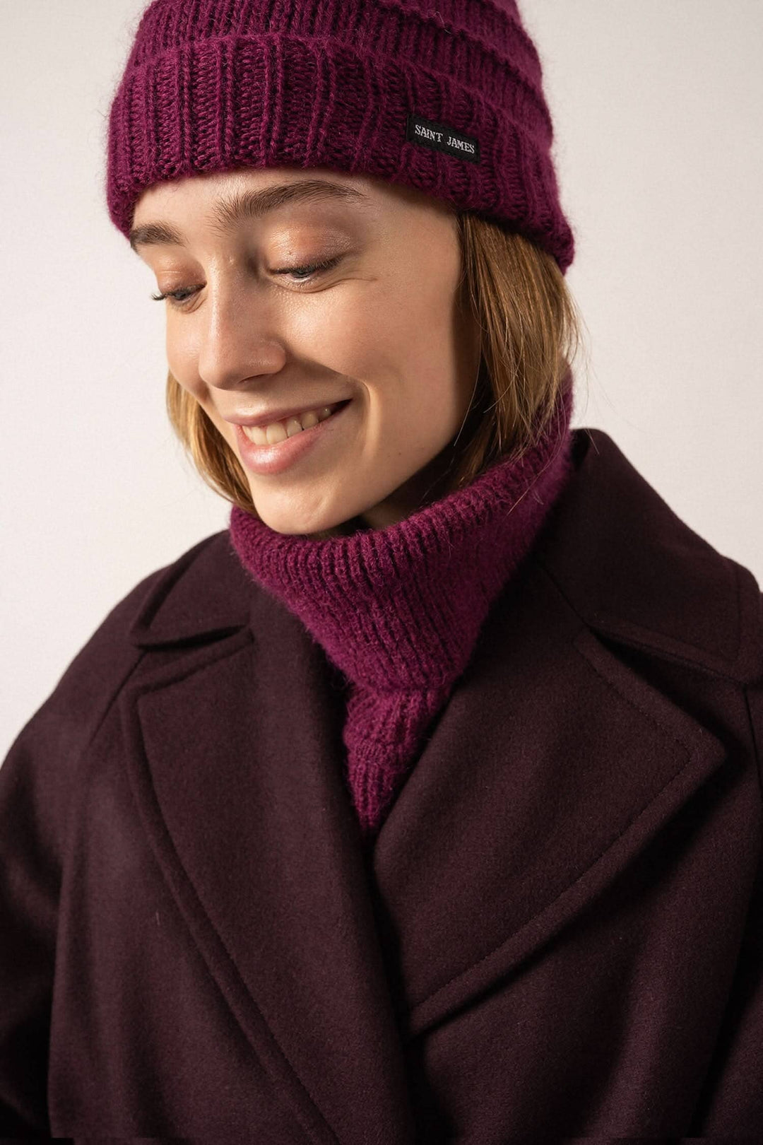 Femme souriante portant une tuque prune tricotée et un col assorti, élégante pour l&