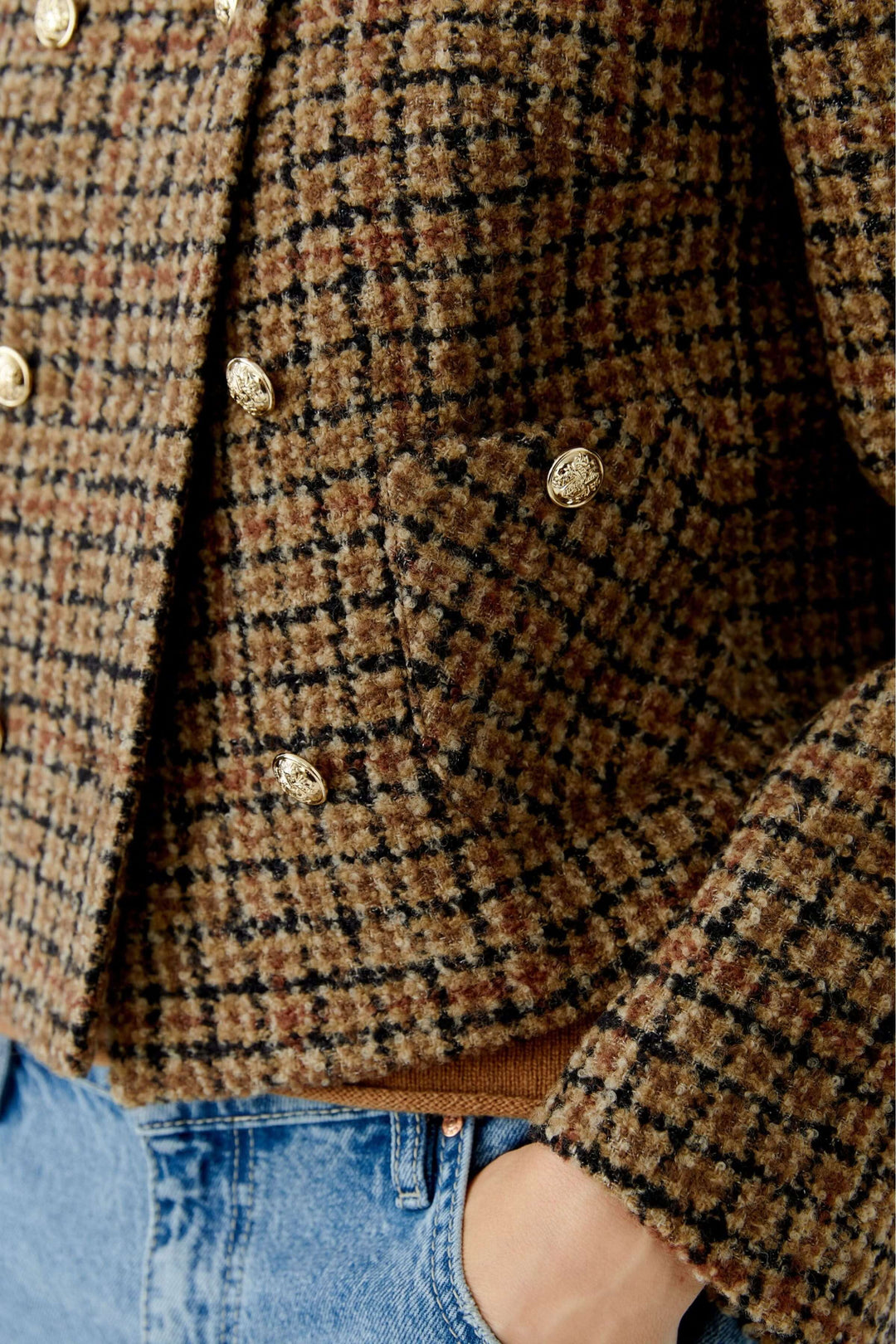Veste courte à carreaux, boutons dorés en lainage texturé, portée avec un jean moderne pour un look élégant et actuel.