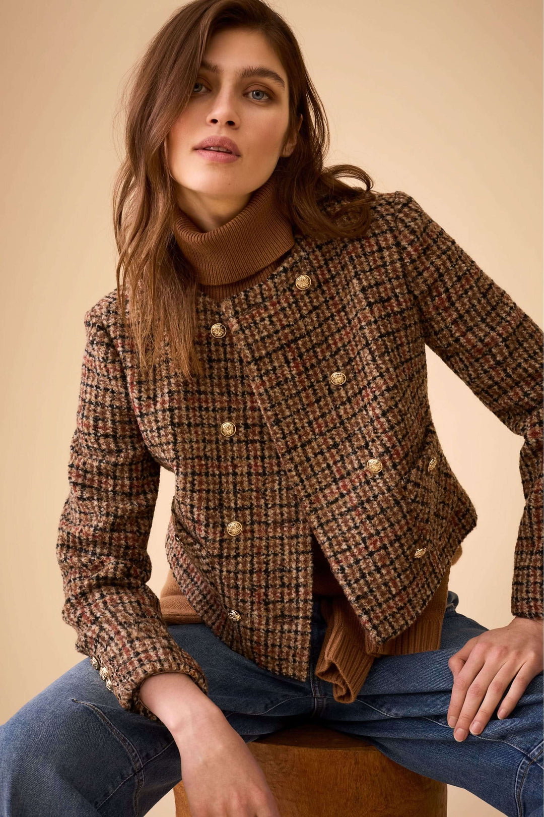Veste courte à carreaux, boutons dorés sur mannequin portant un jean et un col roulé, élégance intemporelle et style moderne.
