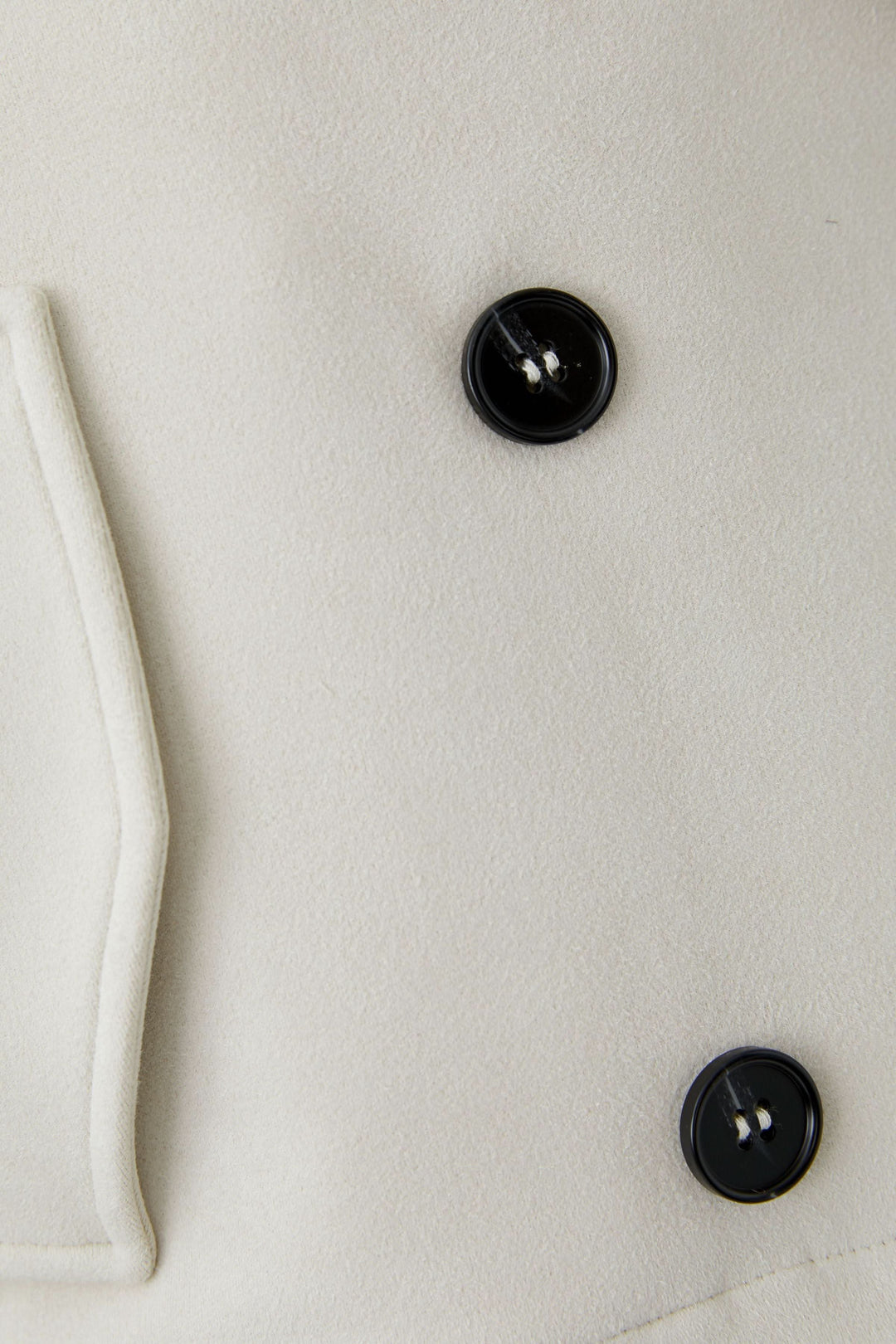 Gros plan sur la Veste courte croisée à col tailleur avec boutons noirs contrastants.