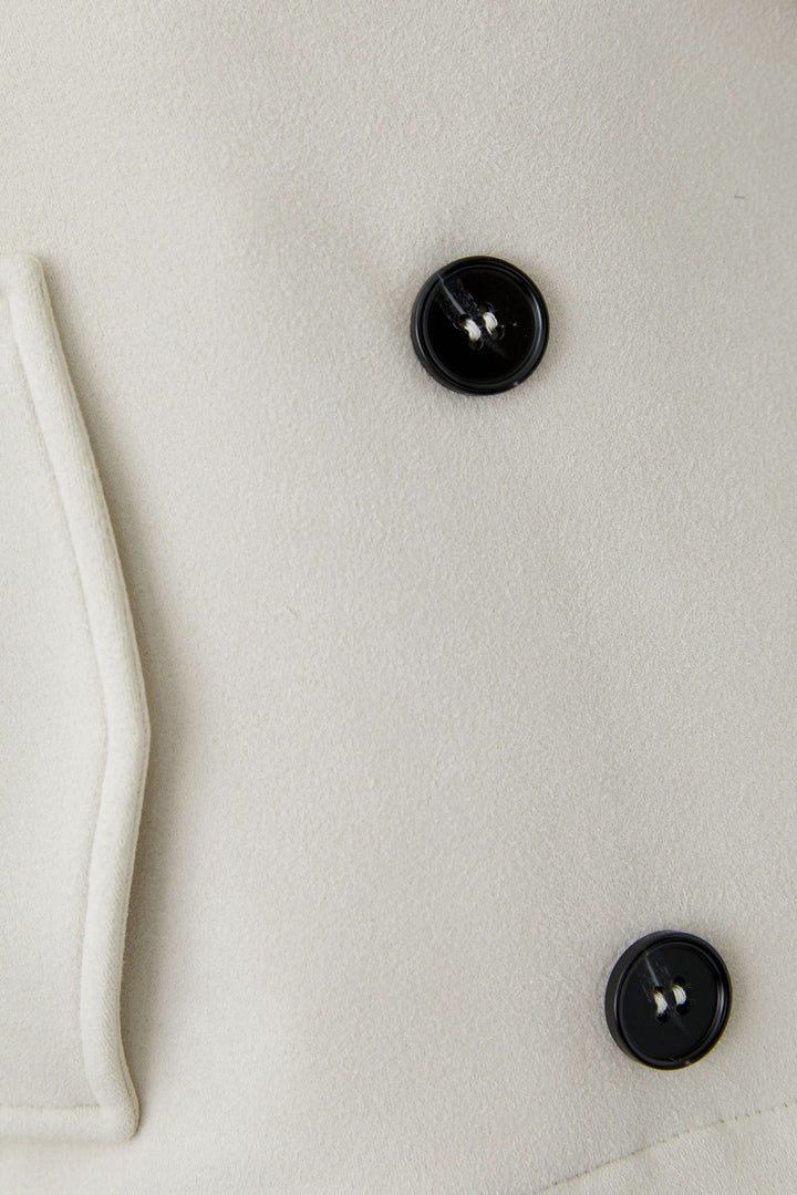 Gros plan sur la Veste courte croisée à col tailleur avec boutons noirs contrastants.