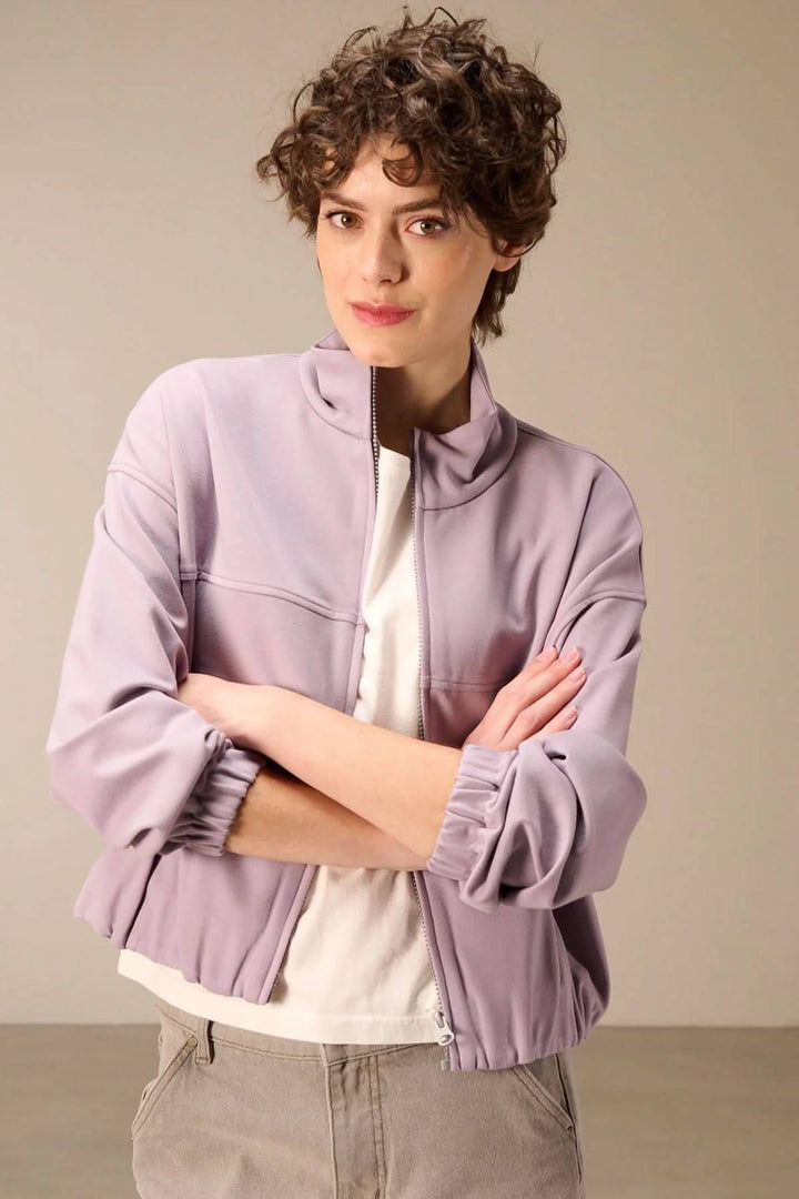 Femme portant une veste en sweat avec fermeture éclair, style moderne et décontracté avec col montant, idéale pour la mi-saison.