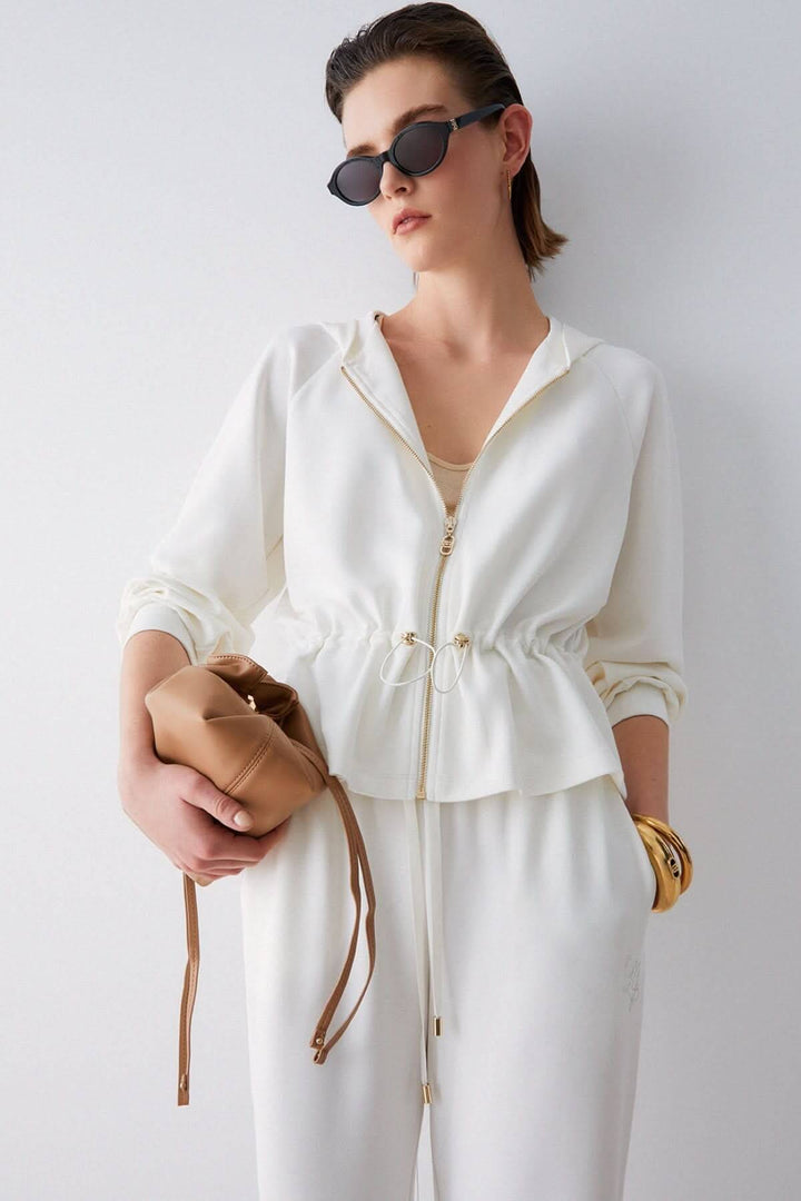 Femme portant une veste légère à capuchon avec cordon ajustable, ajoutant une touche élégante et sportive à sa tenue quotidienne.