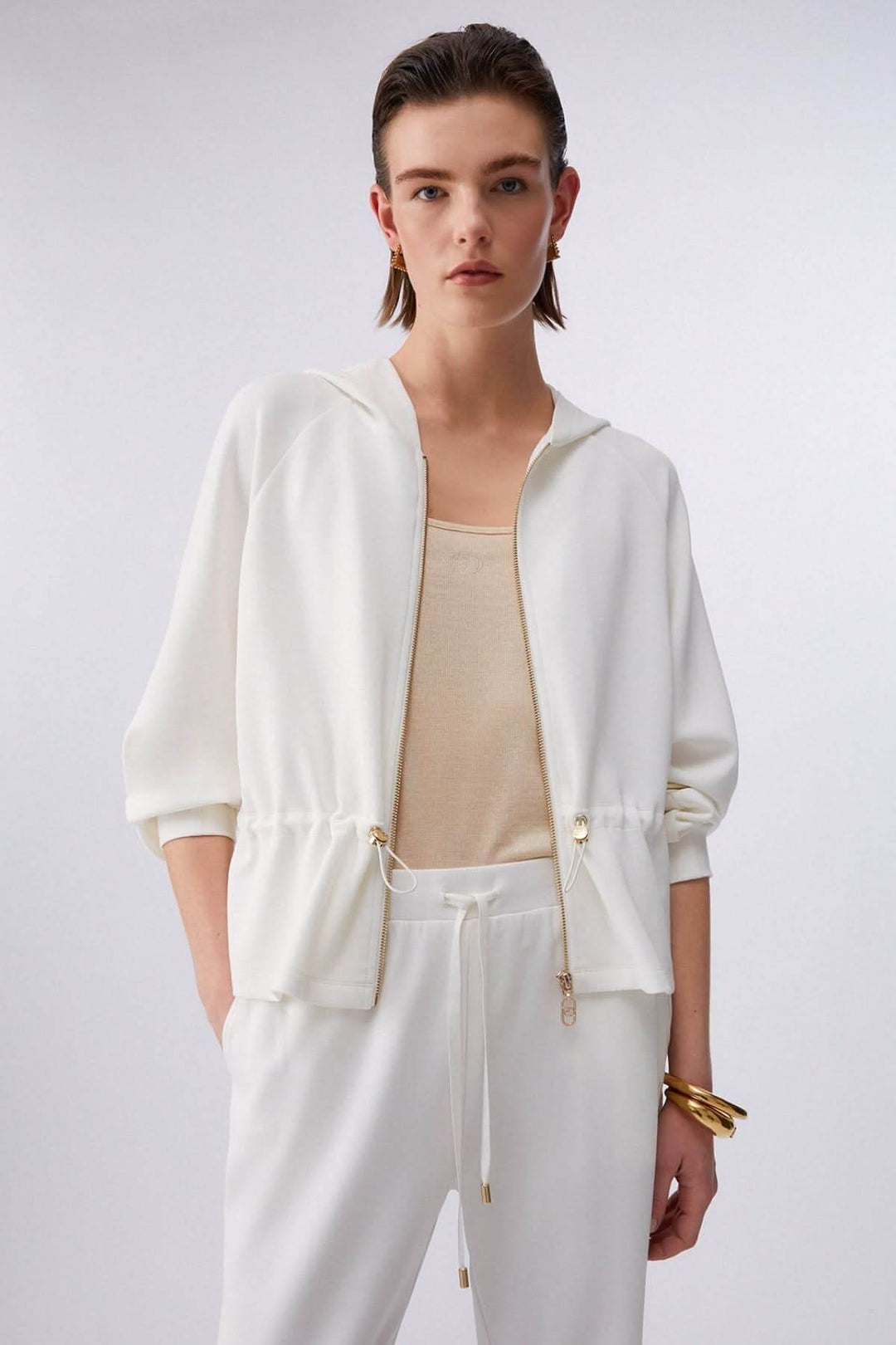 Femme portant une veste légère à capuchon avec cordon ajustable et fermeture à glissière, tenue idéale pour une allure moderne et décontractée.