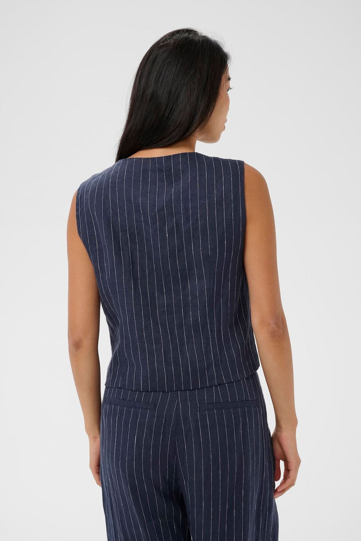 Femme portant une Veste sans manches Azania avec un motif rayé vertical, coupe droite et fermeture boutonnée sur le devant.