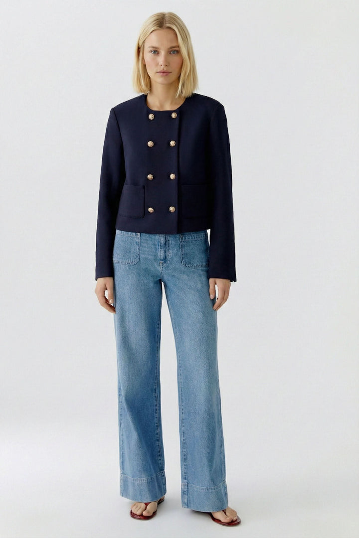 Veste structurée à boutons décoratifs en noir portée sur un jean, mettant en valeur le style chic et sophistiqué.