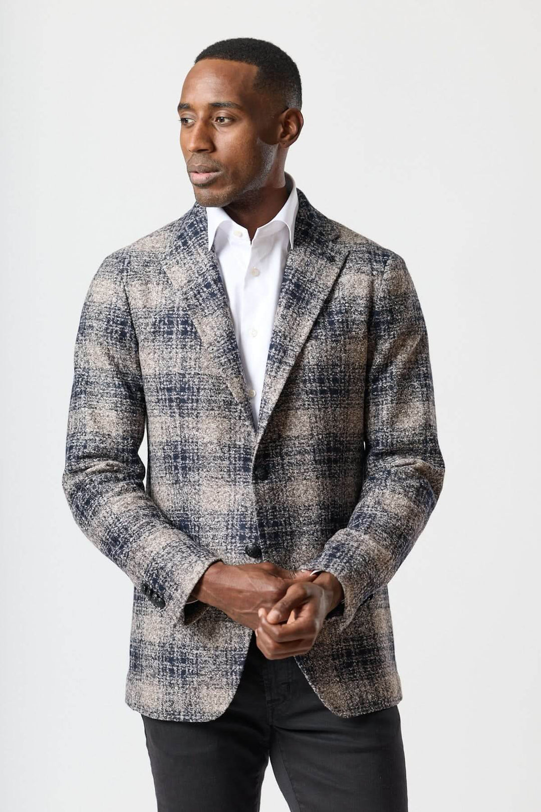 Homme portant un veston à carreaux brossé deux boutons avec une chemise blanche, style urbain élégant.