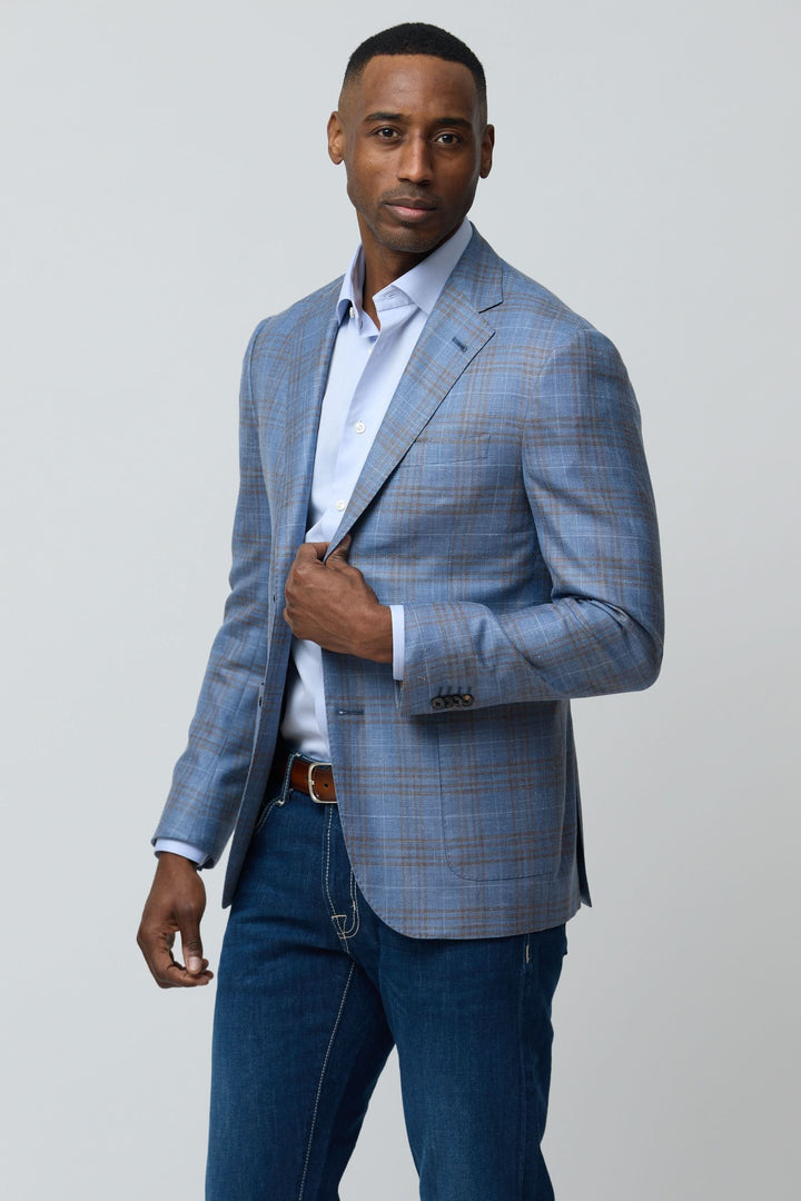 Homme portant un veston à carreaux en laine, soie et lin avec chemise blanche, illustrant élégance moderne et confort décontracté.