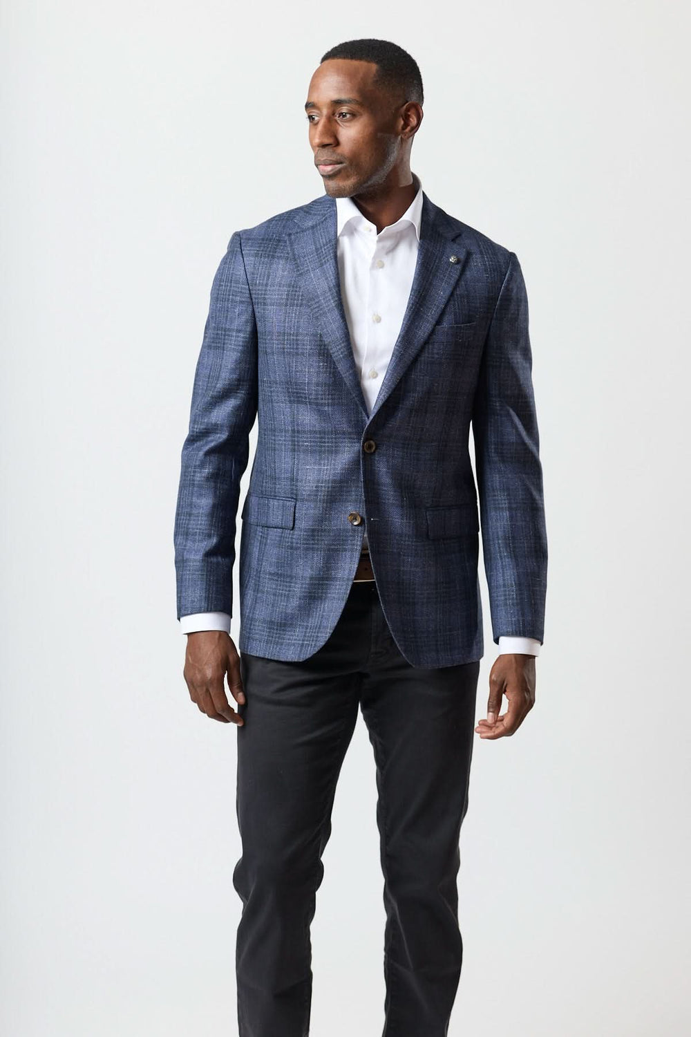 Homme portant un veston à carreaux texturé deux boutons avec chemise blanche et pantalon noir.
