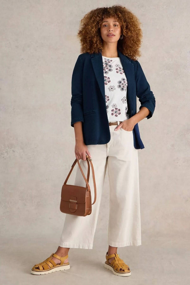 Veston décontracté en denim avec coupe droite, col tailleur classique, porté avec un pantalon clair et t-shirt imprimé pour un look chic.