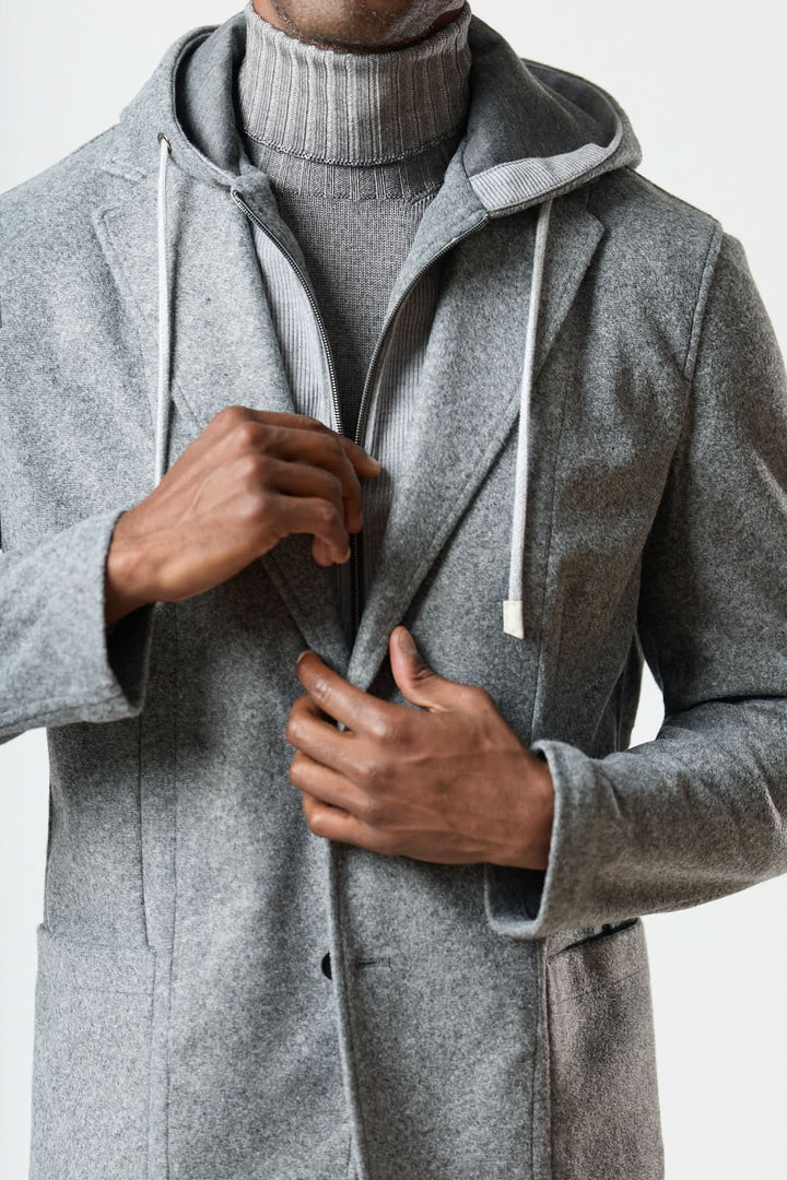 Veston hybride à capuche gris avec fermeture deux boutons porté sur un col roulé pour un style urbain élégant.