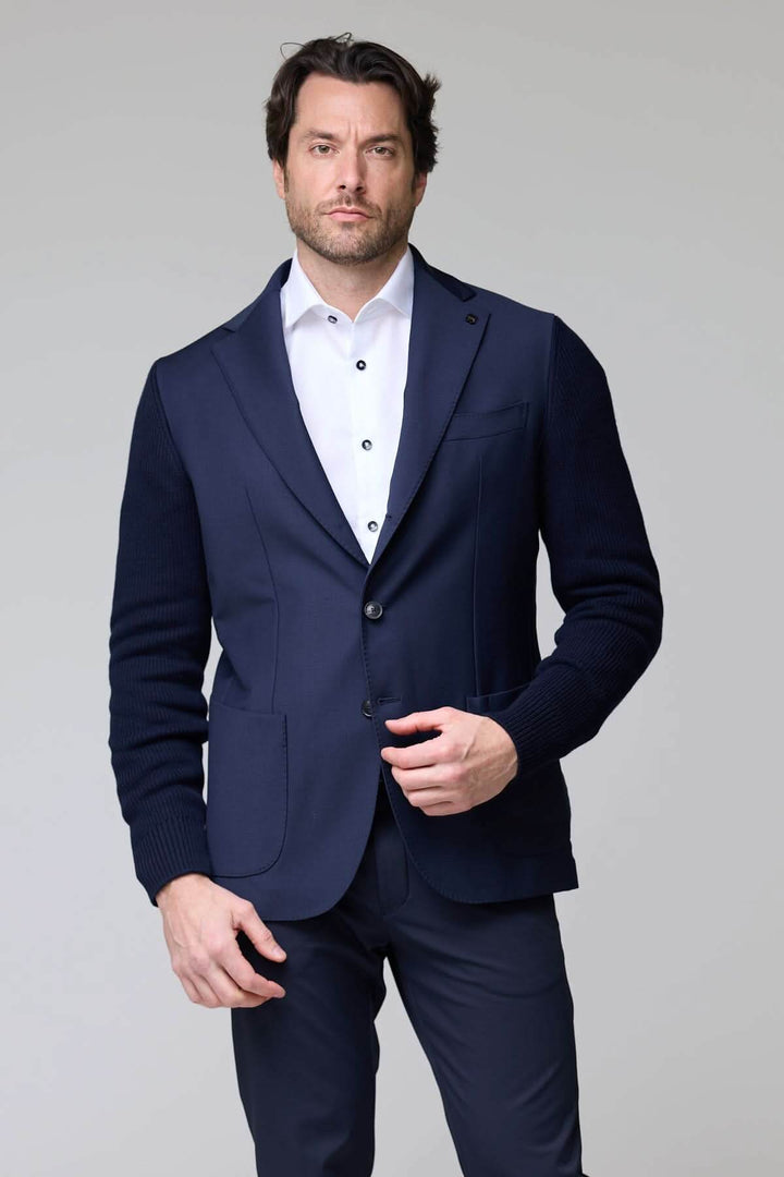 Homme portant un veston hybride tricot et tissu élégant avec manche en maille, col à revers classique et fermeture à deux boutons.