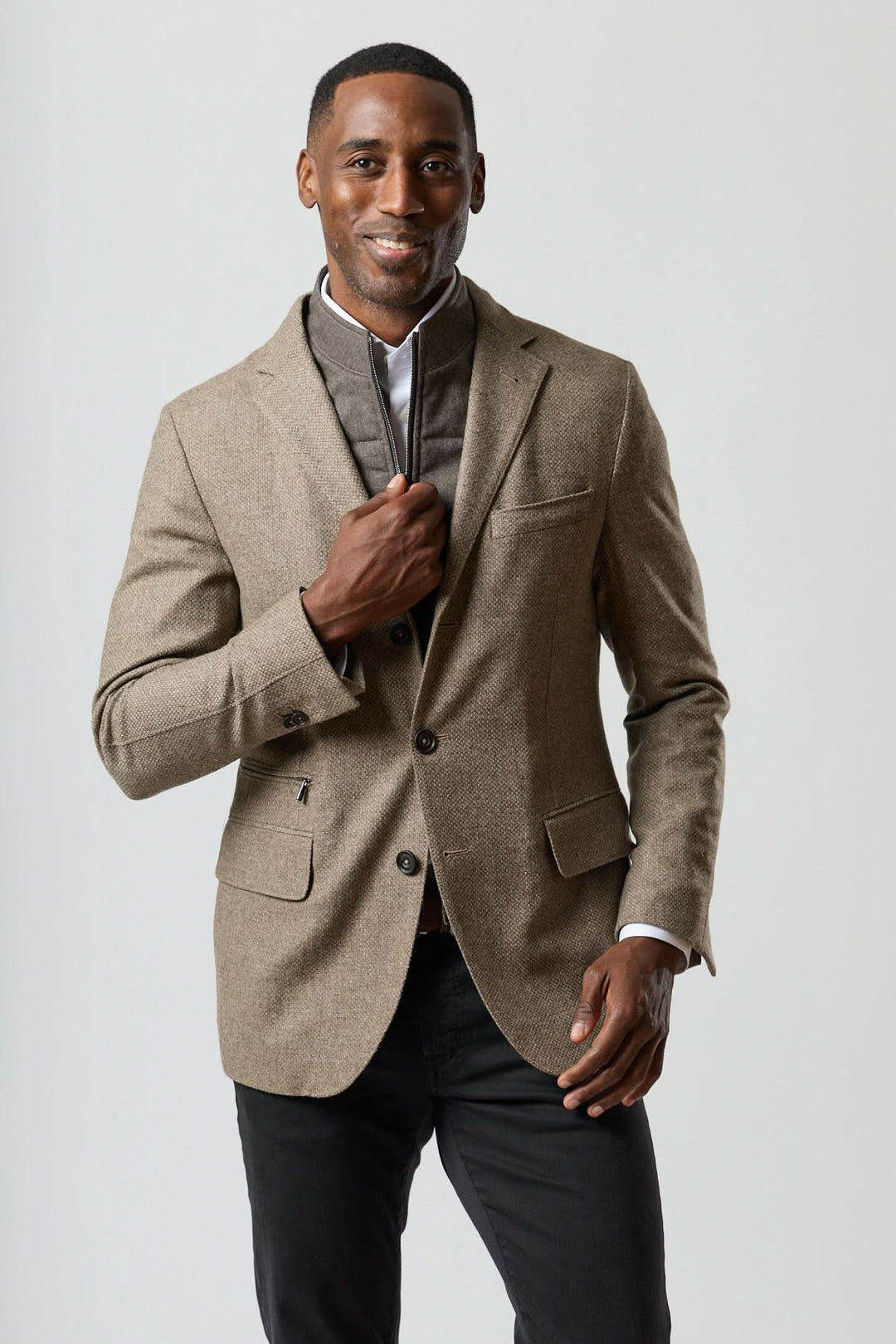 Homme portant un veston texturé en laine avec col amovible intégré en beige doré, style élégant et contemporain.