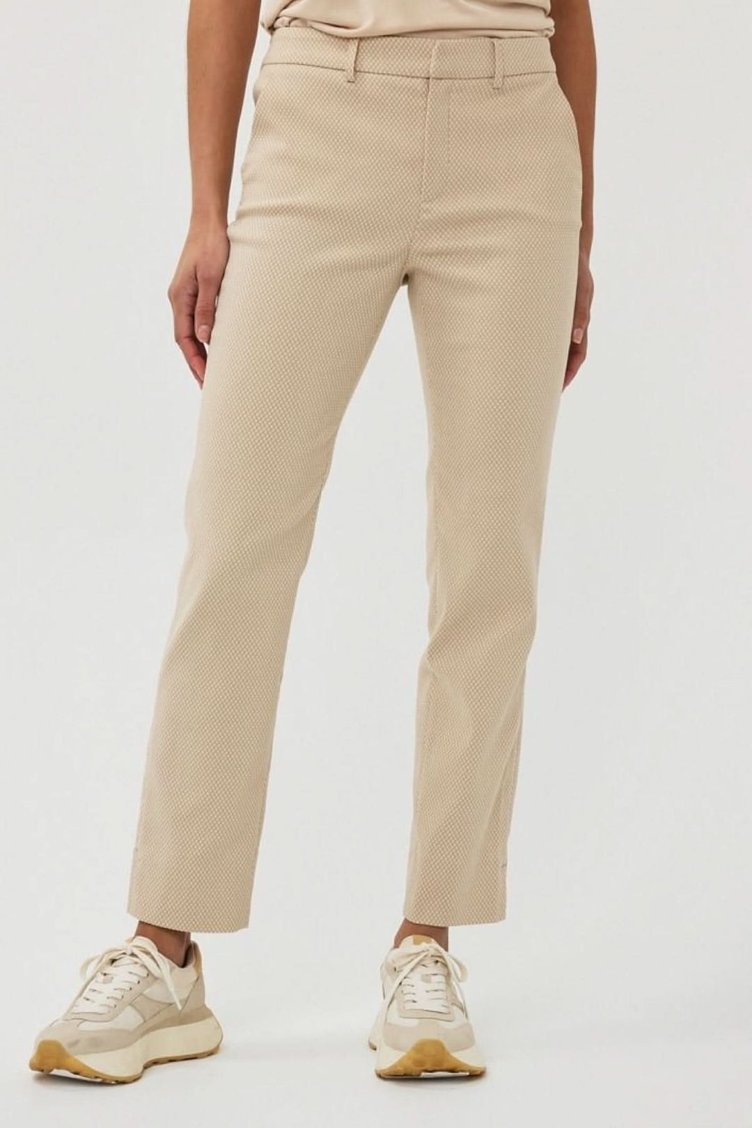 Pantalon en jacquard texturé couleur beige, à taille mi-haute, porté avec des sneakers.