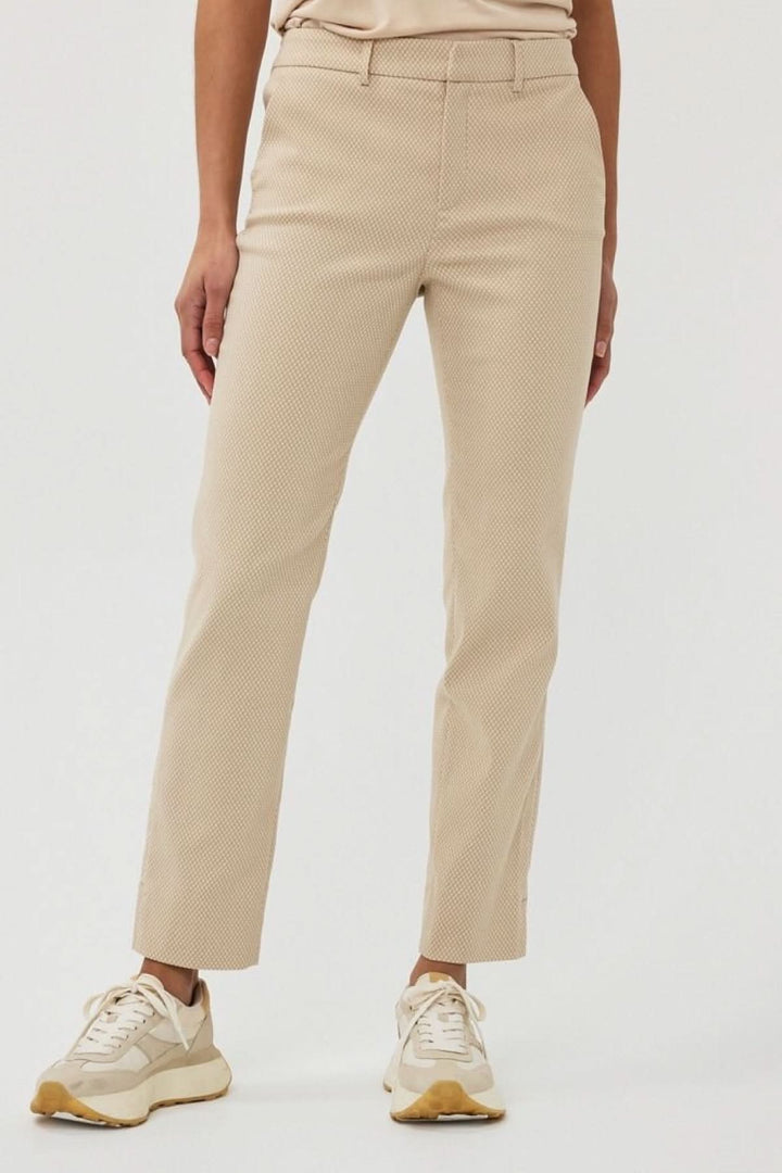Pantalon en jacquard texturé couleur beige, à taille mi-haute, porté avec des sneakers.