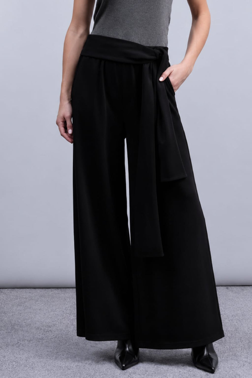 Front view of Haako women's black wide-leg pants with a tied belt - Valérie Simon