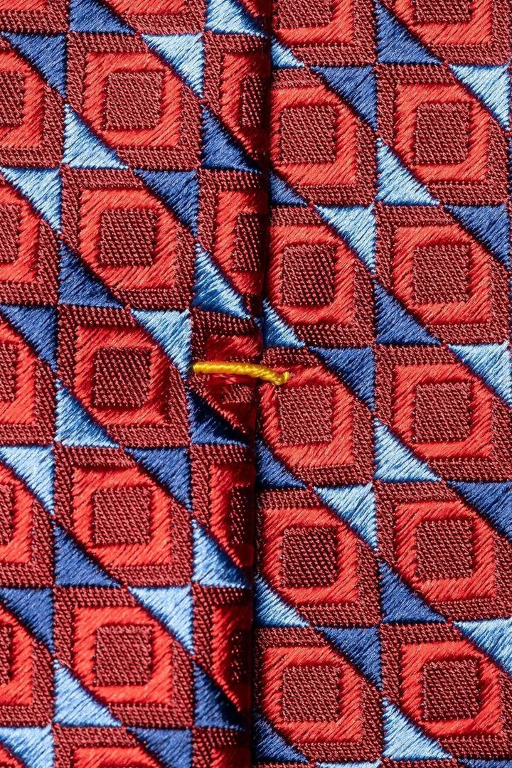 Cravate en soie avec motif géométrique rouge et bleu, ajoutant élégance à une tenue formelle.