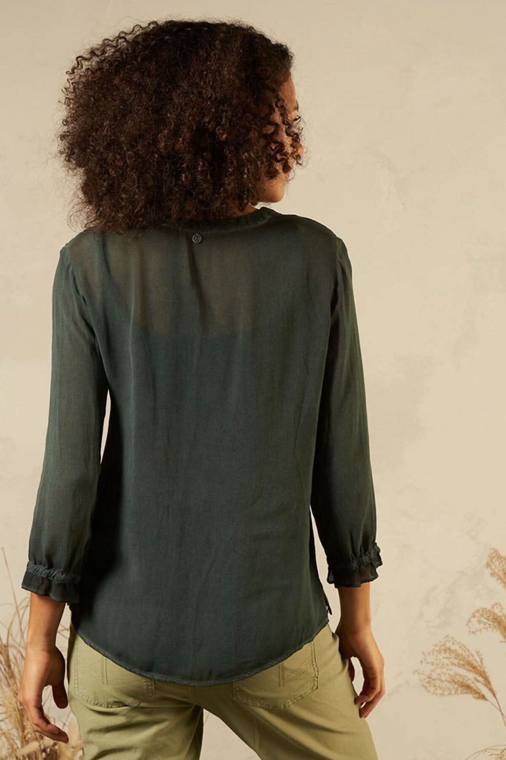 Blouse avec col en V, détails de couture, style décontracté, vue arrière sur mannequin avec cheveux bouclés.