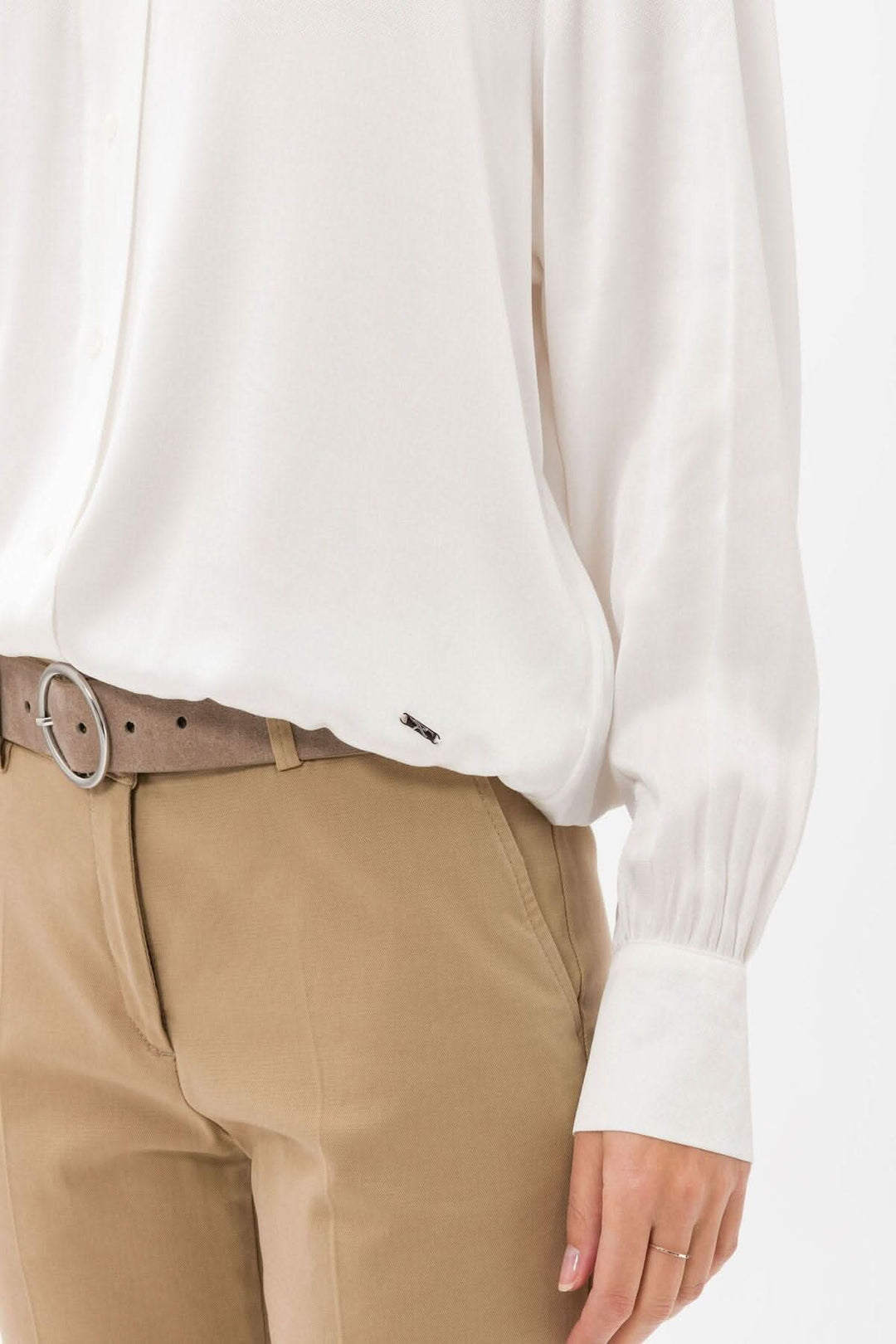 Blouse en viscose blanche à manches bouffantes, portée avec un pantalon beige et une ceinture élégante.