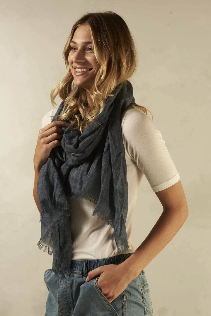 Foulard en laine gris porté par une femme souriante, parfait pour les saisons froides.