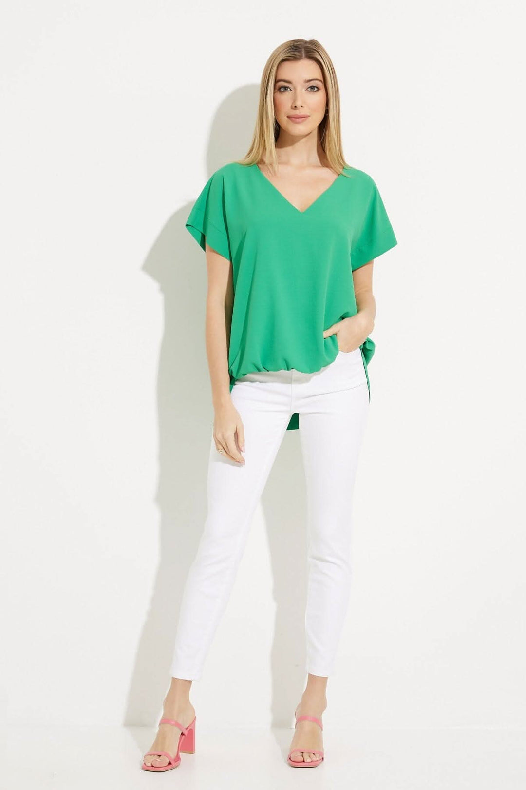 Haut asymétrique vert encolure V avec pantalon blanc, style décontracté et moderne, idéal pour diverses occasions.