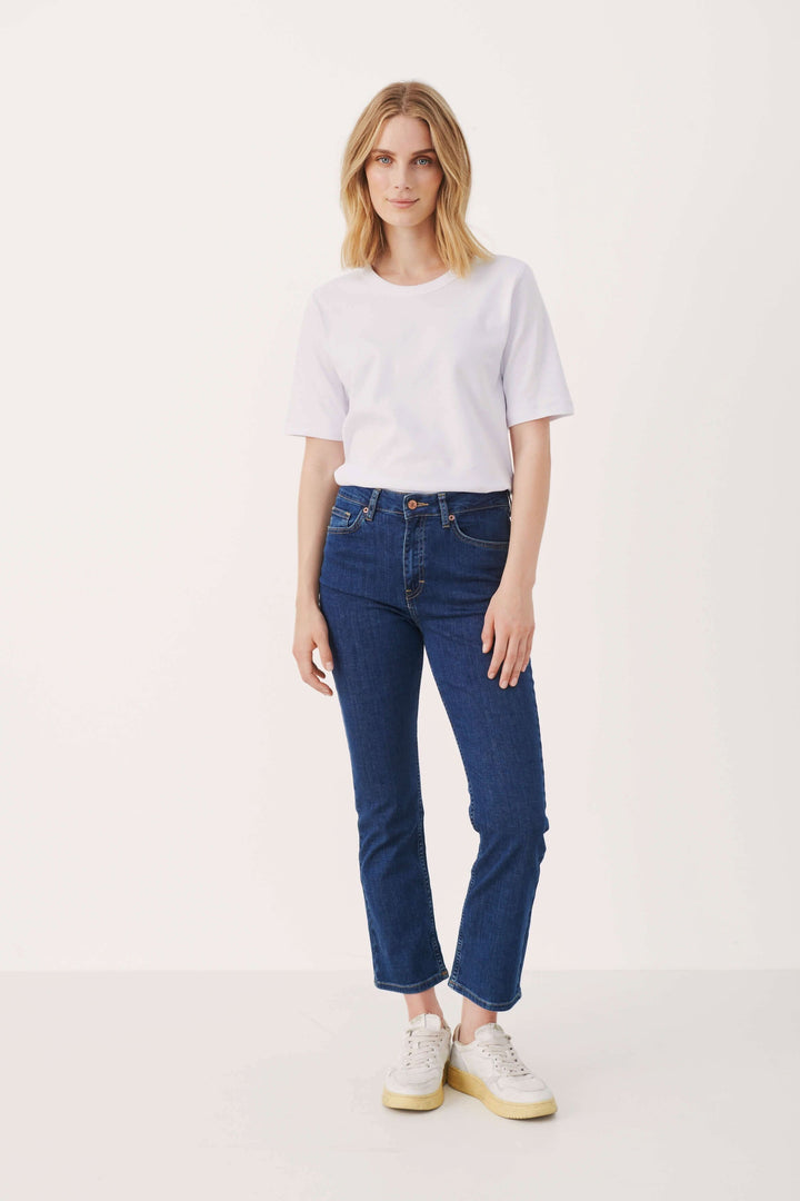 Jean Ryan ajusté à taille haute, style boot leg, longueur au-dessus de la cheville, porté avec un t-shirt blanc.