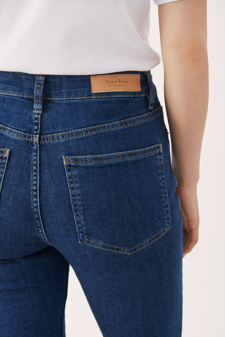 Jean ajusté à taille haute avec poches arrière, bleu foncé, style boot leg, longueur au-dessus de la cheville.