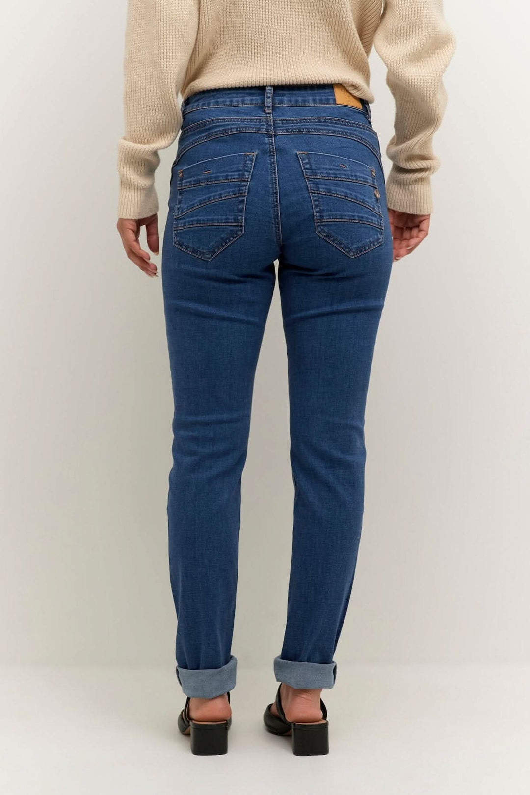 Jean bleu au look décontracté, avec coupe régulière et détails soignés, porté par une femme de dos.