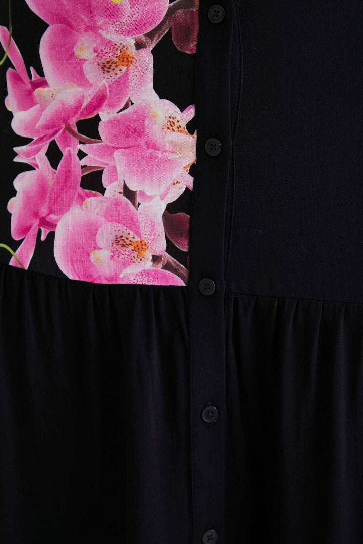 Détail de la jupe longue Christian Lacroix avec imprimé orchidée sur fond noir et boutons centraux.