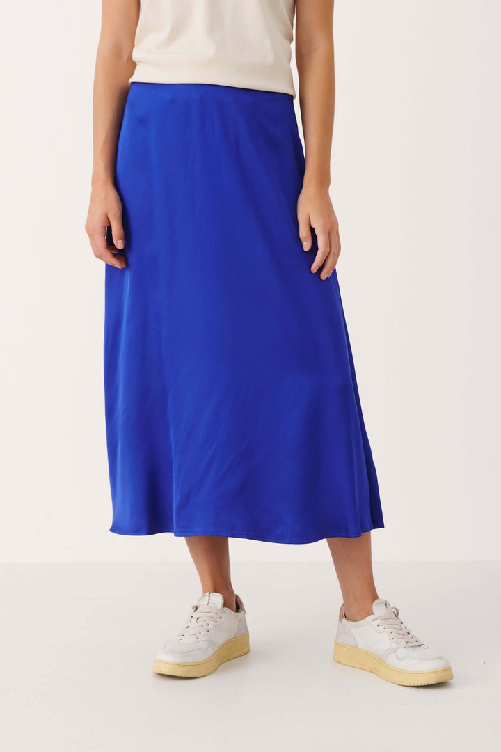 Jupe longue Lilyann en viscose bleu, coupe A, portée avec des baskets blanches, longueur midi.