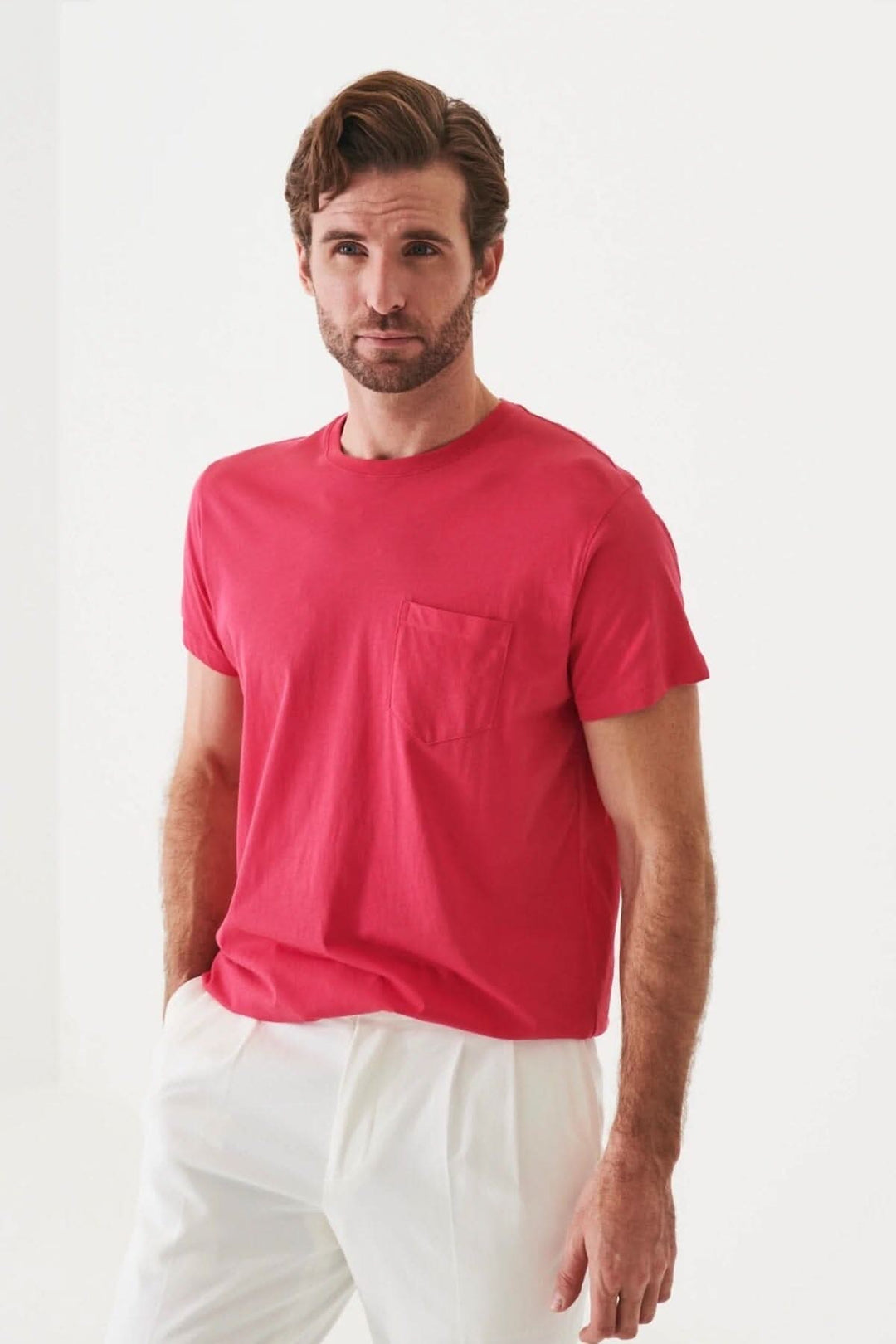 Homme portant un t-shirt léger en coton pima rose avec une poche, conçu pour un ajustement régulier.