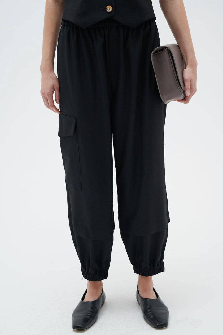 Pantalon cargo noir avec taille élastique, poches avant et sur la jambe, style décontracté.