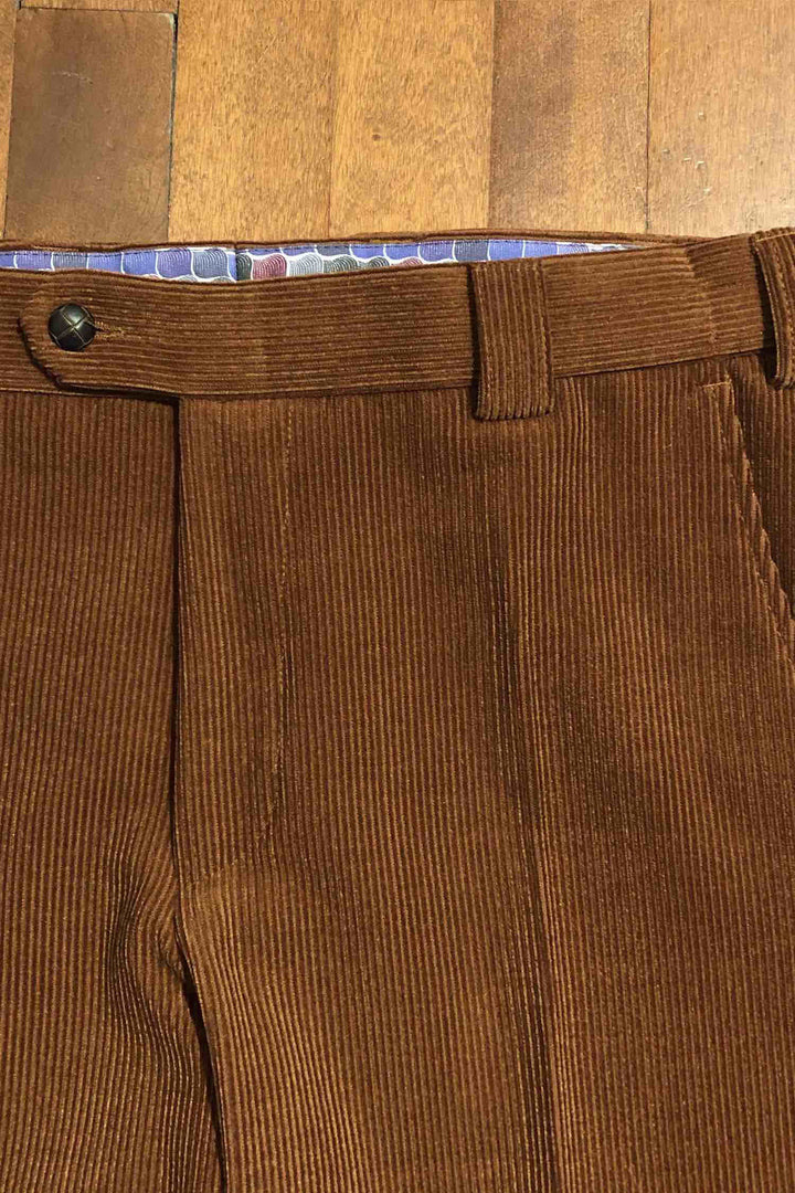 Pantalon en corduroy orange brûlé, coupe régulière, détail de la ceinture et bouton.