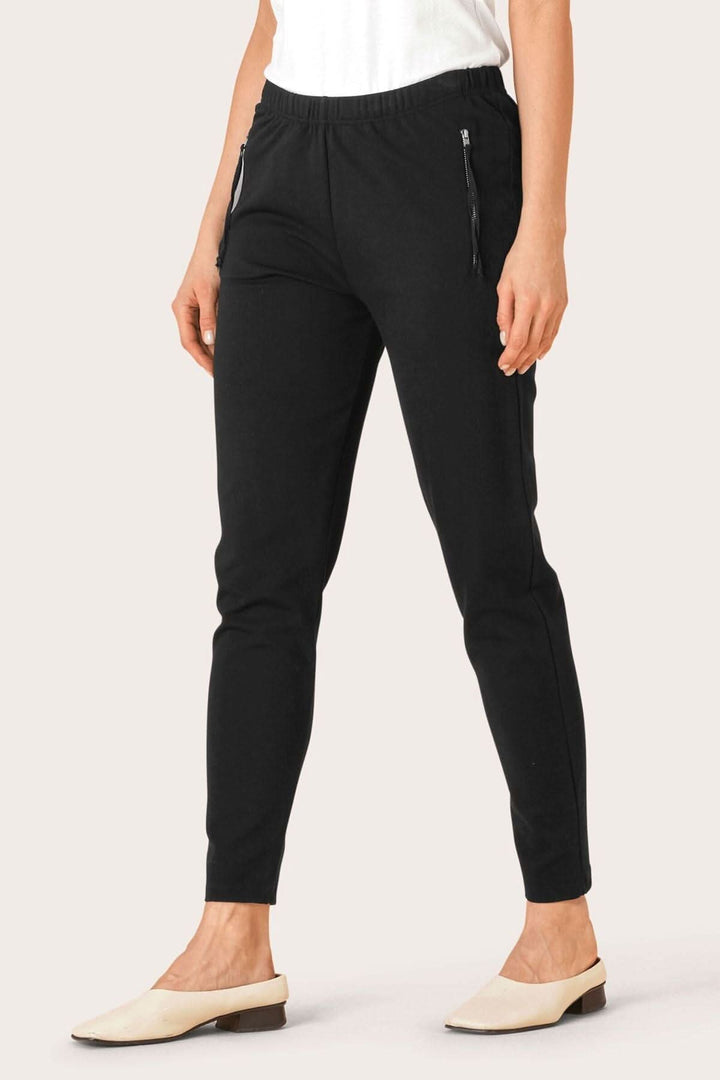 Pantalon en jersey noir avec taille élastique et poches zippées, confortable et moderne.