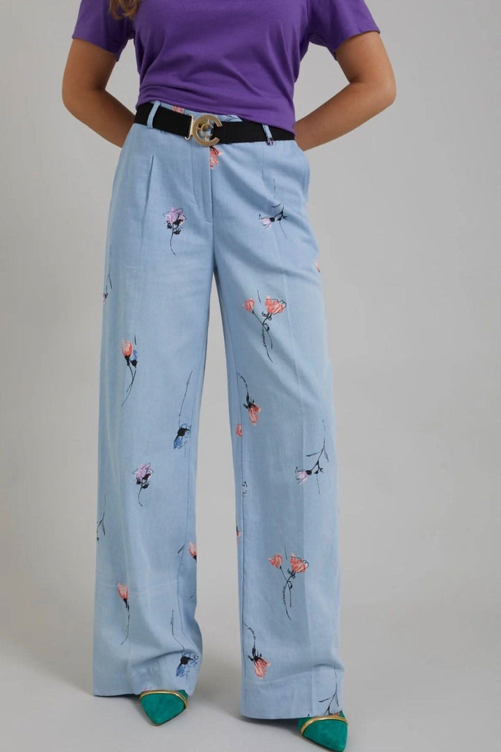 Pantalon large en denim à imprimé floral, coupe décontractée avec t-shirt violet et ceinture noire.