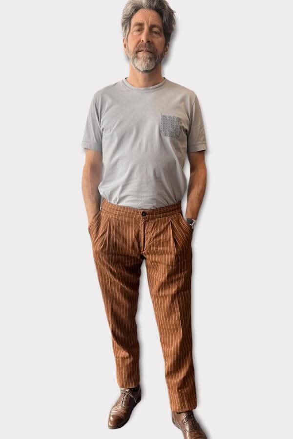 Homme portant un pantalon ligné en lin de couleur marron avec un t-shirt gris, style italien décontracté.