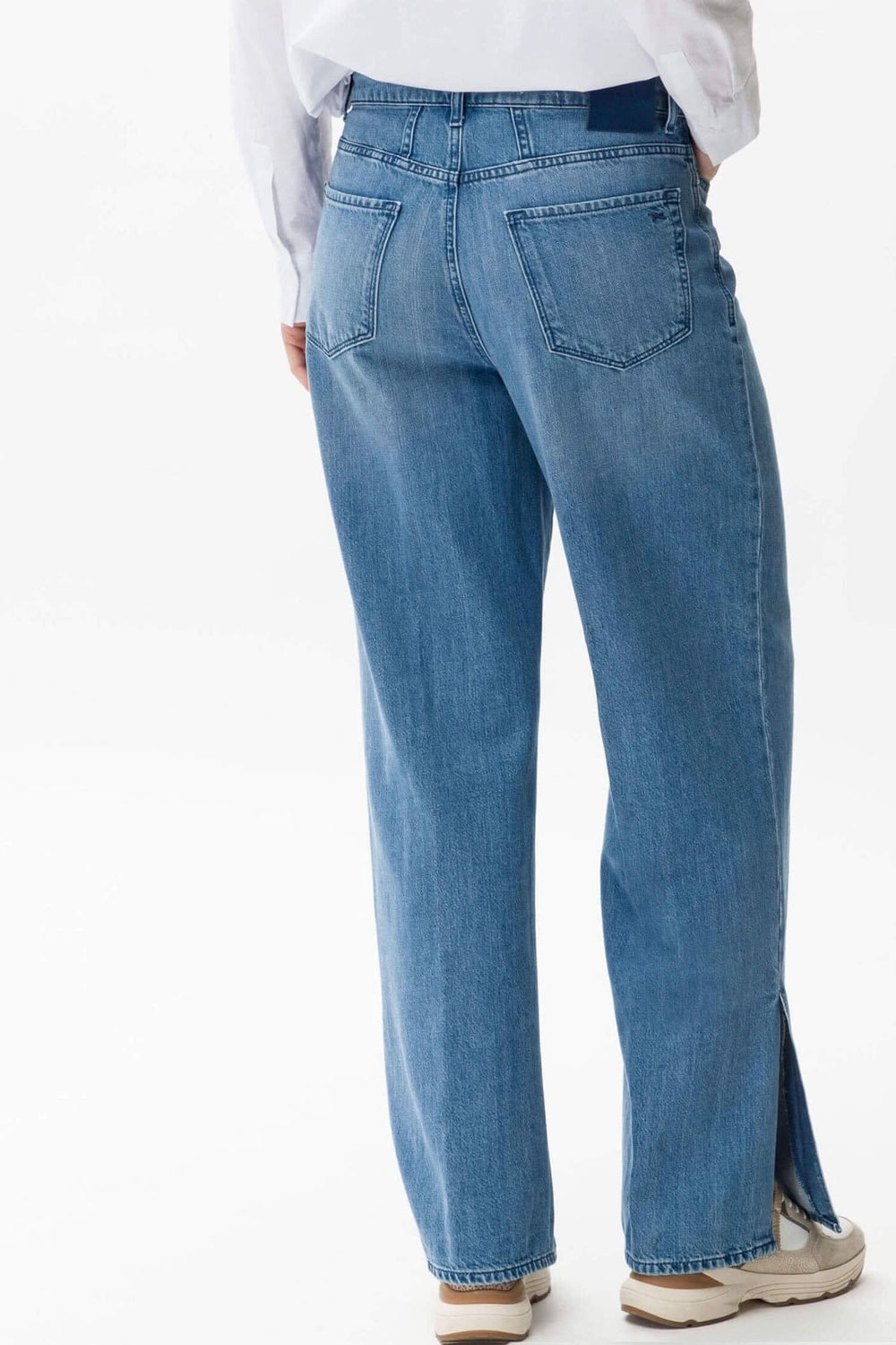 Pantalon Maine en denim bleu avec jambes évasées et fentes d'ourlet, vu de dos.