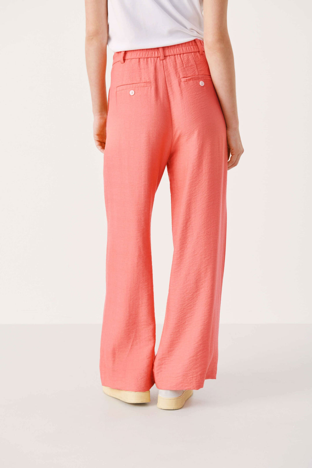 Pantalon Sibille à jambe large, tissu fluide, couleur corail, vu de dos avec détails de poches.