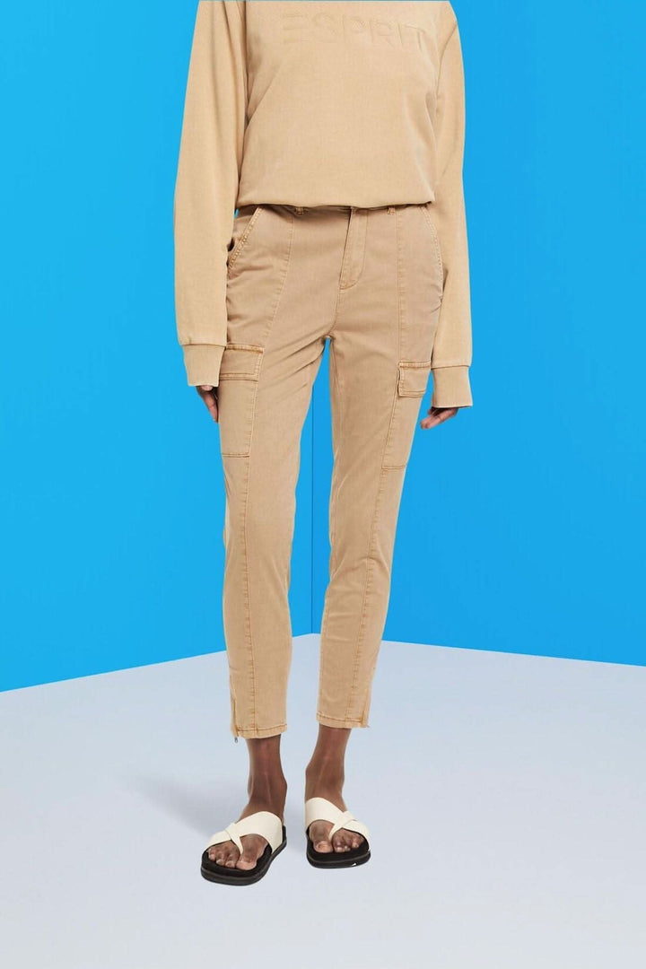 Pantalon taille mi-haute style cargo beige pour femme, associé à un haut confortable sur fond bleu.