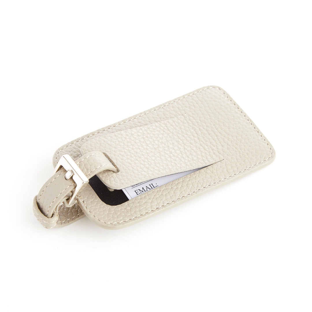 Étiquette à bagages en cuir beige, élégante et pratique, avec espace pour informations personnelles.