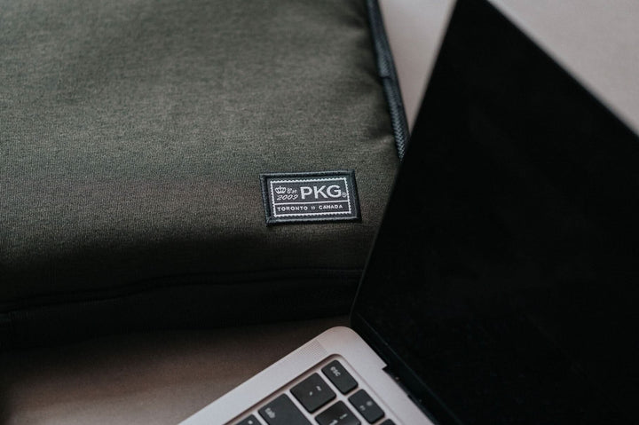 Pochette pour ordinateur portable PKG Stuff sur une surface avec un ordinateur portable à côté.