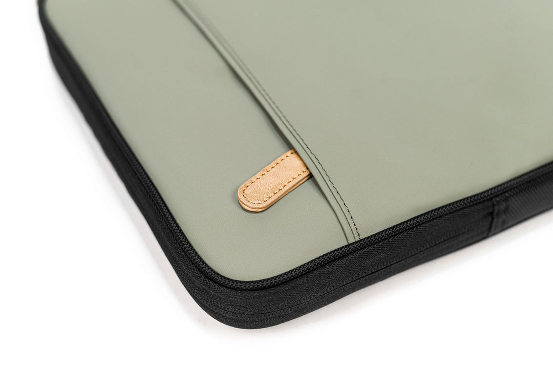 Pochette pour ordinateur portable de couleur vert olive avec fermeture éclair et détail en cuir.