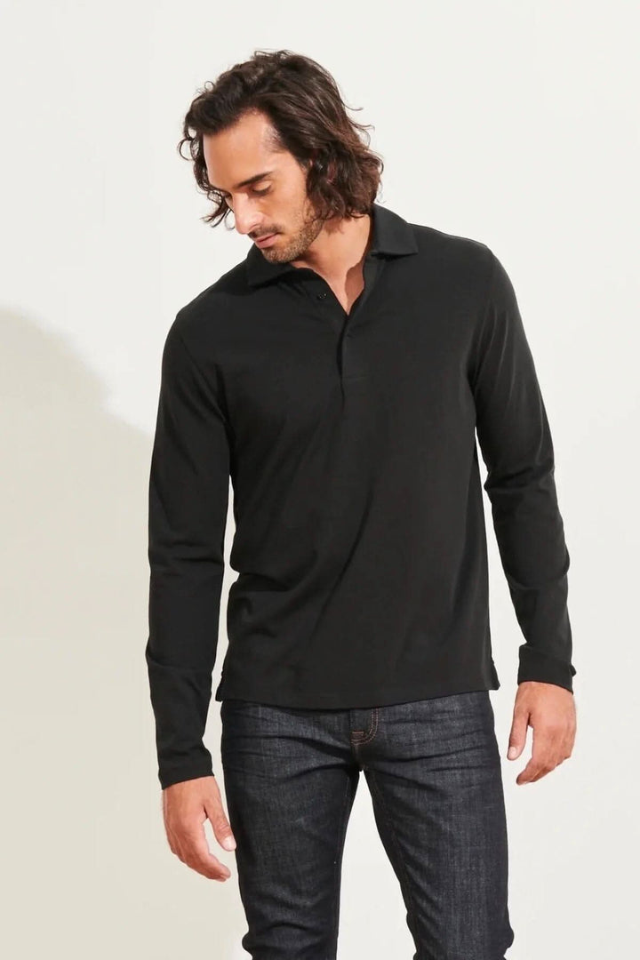 Homme portant un polo noir à manches longues en coton stretch, associé à un jean décontracté.