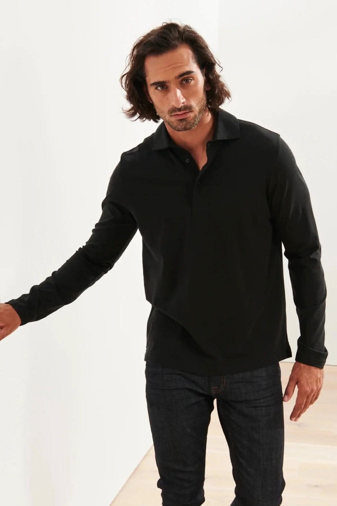 Homme portant un polo en coton stretch noir à manches longues, avec un style décontracté.