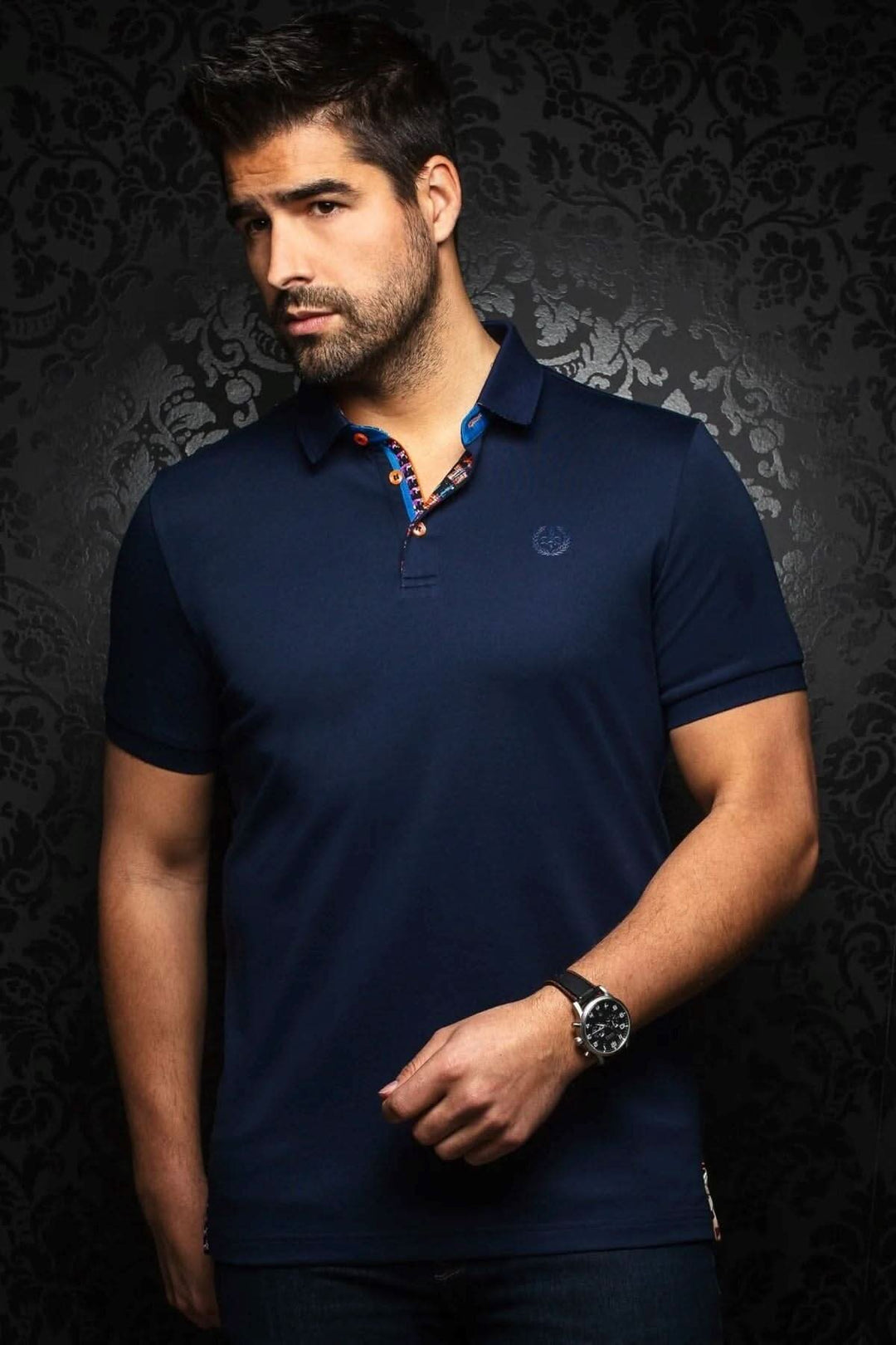 Homme portant un polo bleu foncé avec col contrastant et broderie, élégant et décontracté, en coton haut de gamme.