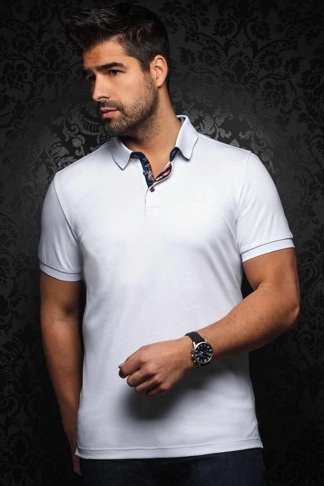 Homme portant un polo blanc, col contrastant et détails sophistiqués, style décontracté et habillé.