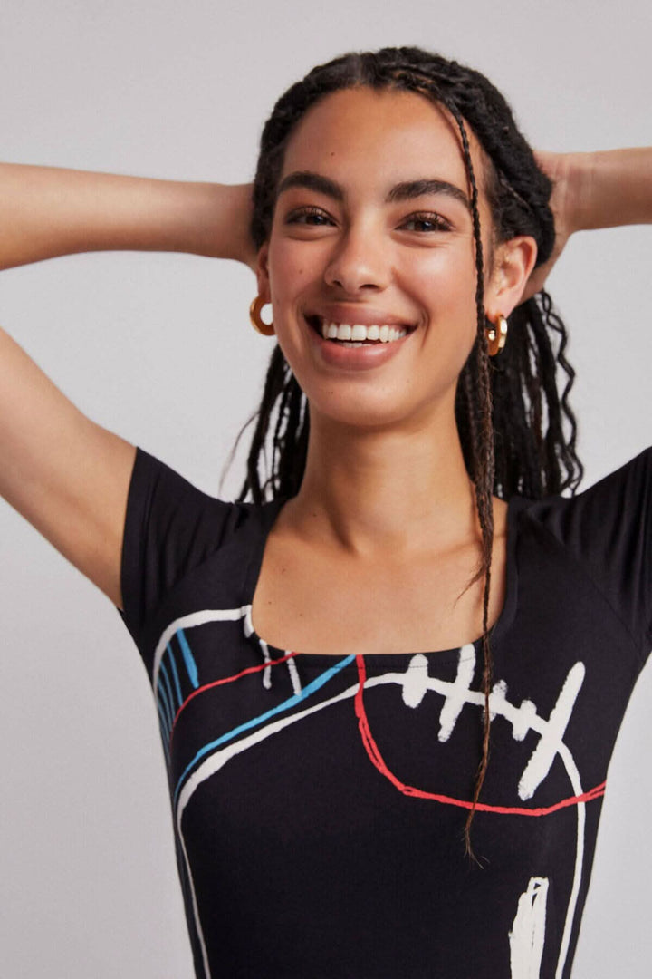 Femme souriante portant une robe longue à imprimé artistique avec des manches courtes et une encolure carrée.