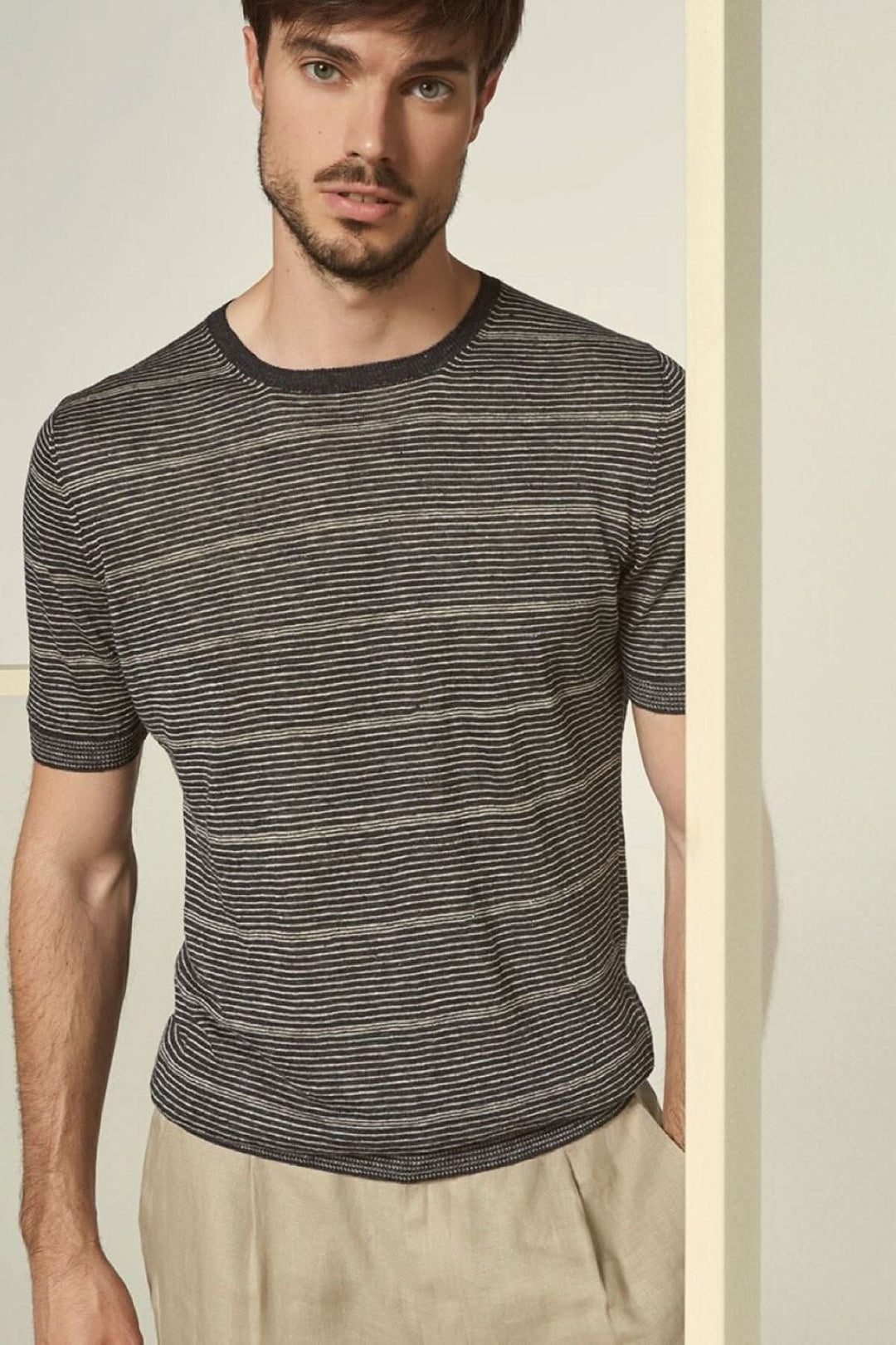 Homme portant un t-shirt à rayures avec col rond et manches courtes, associé à un pantalon clair.