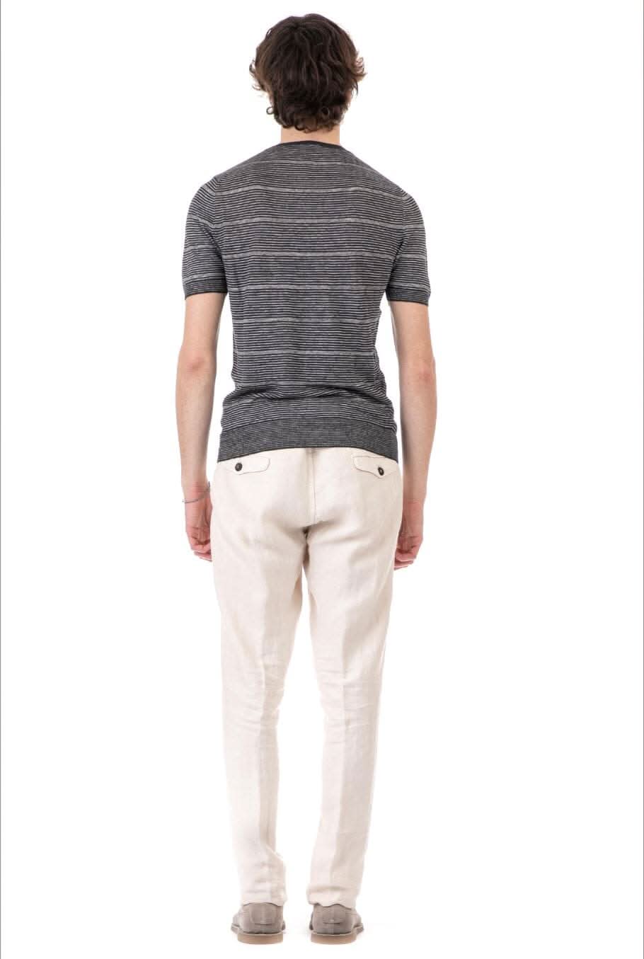Homme de dos portant un t-shirt à rayures avec pantalons clairs, style décontracté.