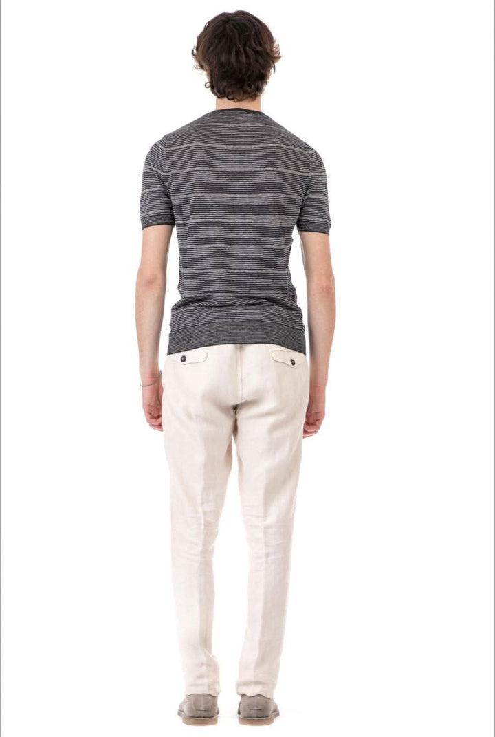 Homme de dos portant un t-shirt à rayures avec pantalons clairs, style décontracté.